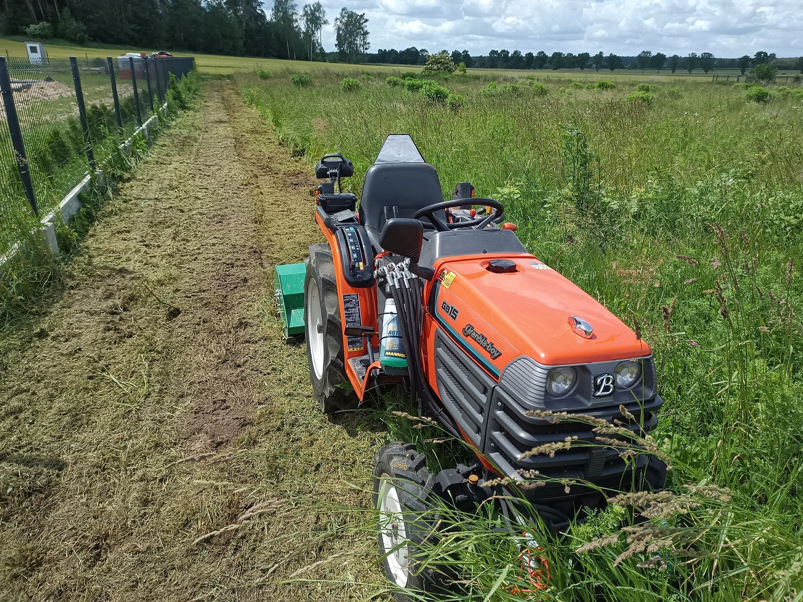 Ciągnik z kosiarką bijakową w wysokiej trawie